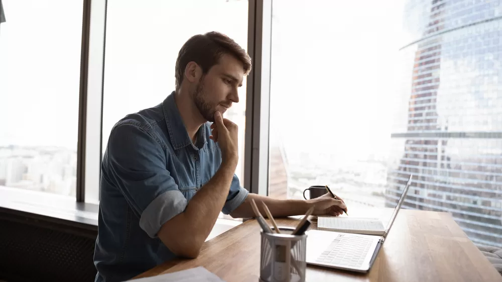 A person sitting at a desk with a laptop, understanding Dilapidation Reports